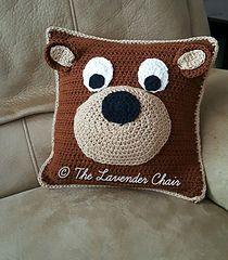 a crocheted bear pillow sitting on top of a couch