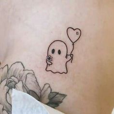 a woman's stomach with a ghost holding a heart balloon tattoo on her left side