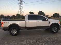 a white pickup truck parked in a parking lot next to power lines and telephone poles