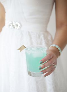 a woman in a white dress holding a green drink