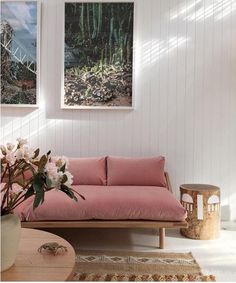 a living room with pink couches and pictures on the wall above it, along with flowers