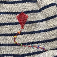 a striped sweater with a red flower on it