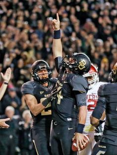 the football players are giving each other high fives in front of an excited crowd