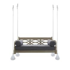 a swing bed with grey cushions and two white pom poms hanging from it