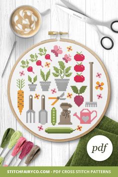 a cross stitch pattern with flowers and gardening tools on it, next to some scissors