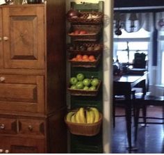 a tall wooden cabinet sitting next to a wall filled with baskets and fruit on top of it