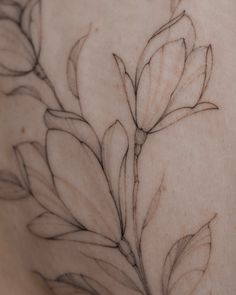 the back of a woman's breast with flowers drawn on her chest and behind it is a drawing of leaves