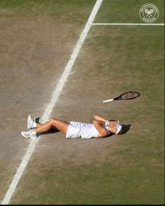 a woman laying on the ground with a tennis racquet in her hand,