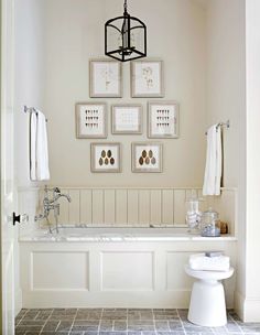 a white bathroom with pictures on the wall