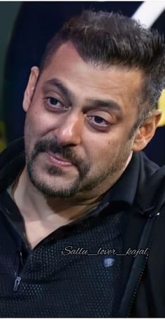 a close up of a person wearing a black shirt and looking at the camera with an intense look on his face