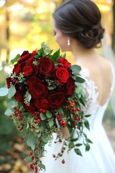 a bride holding a bouquet of red roses