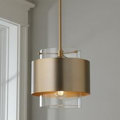 a light fixture hanging from the ceiling in a room with white walls and window sill