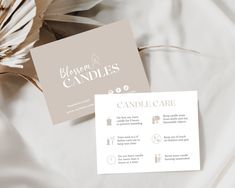 a close up of a business card on top of a white bed with flowers in the background