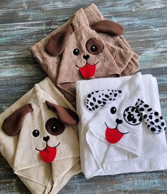 three towels with dog faces on them sitting on a wooden floor next to each other