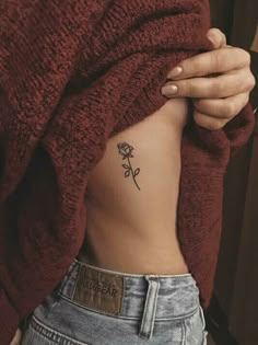 a woman with a rose tattoo on her stomach is holding the back of her body