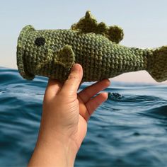 a hand holding a stuffed fish in the water