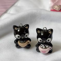 two black and white cat figurines sitting next to each other on a bed