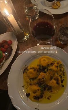 a white plate topped with food on top of a table next to glasses of wine