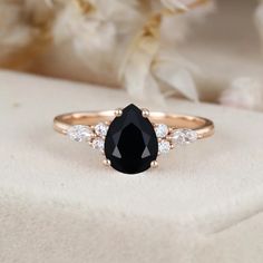 a black and white diamond engagement ring on top of a flowered cloth with flowers in the background