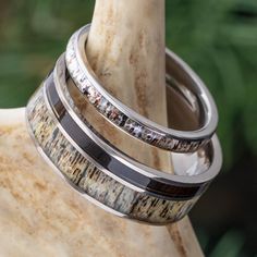 two wedding bands with white and brown stones on them sitting on top of a rock