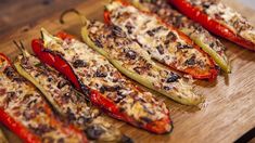 several peppers on a wooden cutting board with cheese and seasoning sprinkles