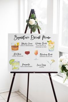 a sign that is on top of a easel with drinks in it and flowers