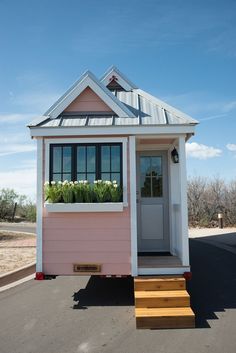 a tiny pink house sitting on the side of a road