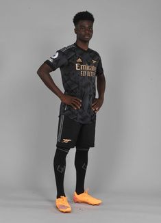 a young man in black and yellow soccer uniform standing with his hands on his hips