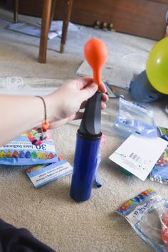 a person holding an orange object in their hand on the floor next to other items