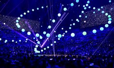 the stage is lit up with blue lights and balloons floating in the air above it