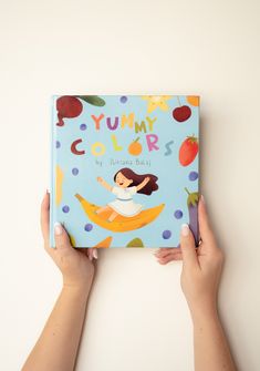 a person holding up a book with the title yummy colors