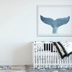 a baby's room with a white crib, black and white bedding, and a whale tail print on the wall