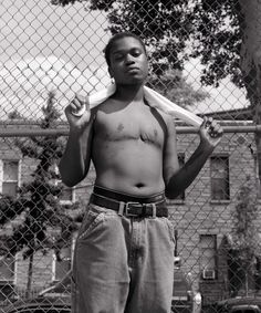 a man standing in front of a chain link fence with his shirt open and no shirt on