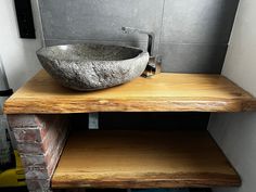 a bathroom sink sitting on top of a wooden counter next to a brick wall with a mirror above it