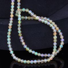 a multicolored glass beaded necklace on a black surface with a metal clasp