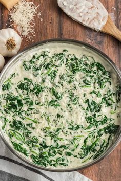 spinach dip in a bowl with cheese and garlic on the side next to bread