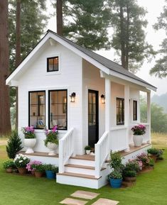 a small white house with potted plants on the front porch and steps leading up to it