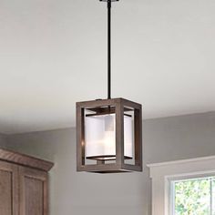 a light fixture hanging from the ceiling in a kitchen with wooden cabinets and white walls