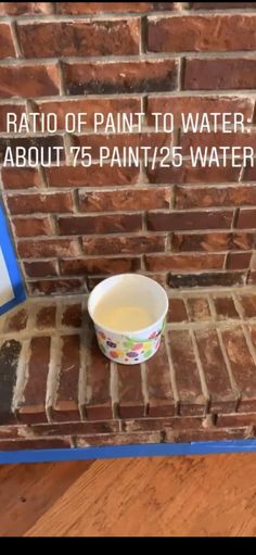 a bowl of paint sitting on top of a brick wall