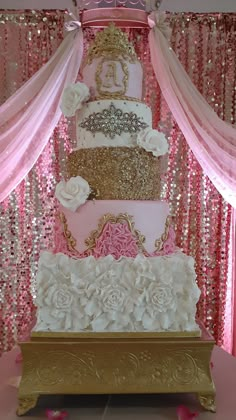 a three tiered cake sitting on top of a wooden table covered in pink and gold sequins