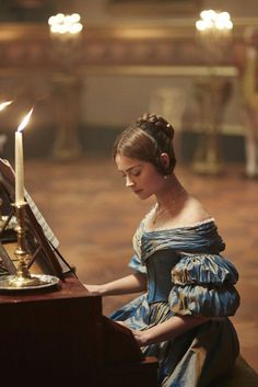 a woman sitting at a table with a candle in her hand