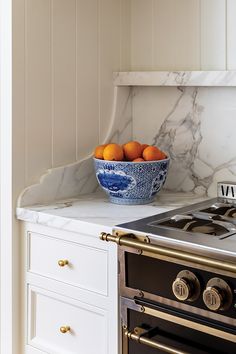 a bowl of oranges sitting on top of a kitchen counter next to an oven