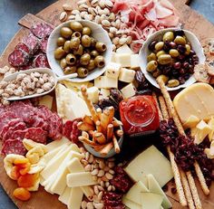 a wooden platter filled with different types of cheese and meats on top of each other