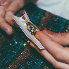 a person is holding a toothbrush with sprinkles on it and the woman's hands are next to her