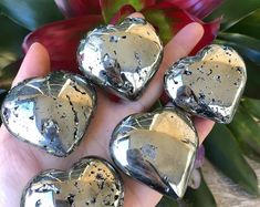 three heart shaped pieces of metal sitting on top of a wooden table next to flowers