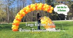 an arch made out of balloons in the grass with a person walking under it and another sign that says large balloon arch balloon decoration