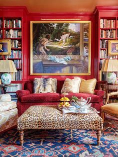 a living room filled with lots of red furniture and bookshelves full of books