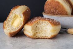 two pieces of bread with butter spread on them next to a knife and bowl filled with powdered sugar