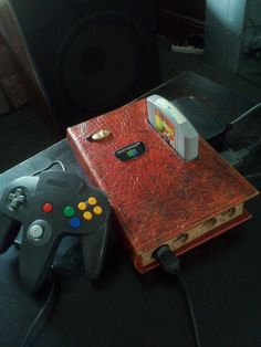 a video game console and controller sitting on top of a wooden table next to a speaker