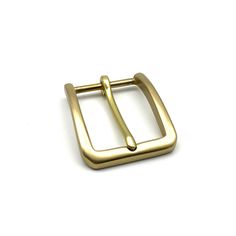 a gold buckle on a white surface with a clip in the shape of a rectangle